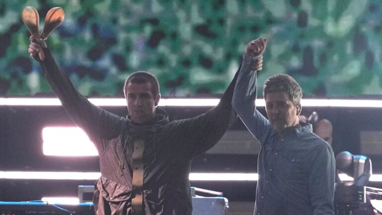 Gallagher brothers share a high-five and hug as Oasis reunite on stage after 16 years
